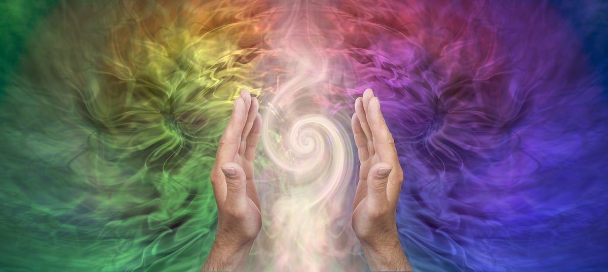 Two hands cupping a swirl of colorful golden and violet energy